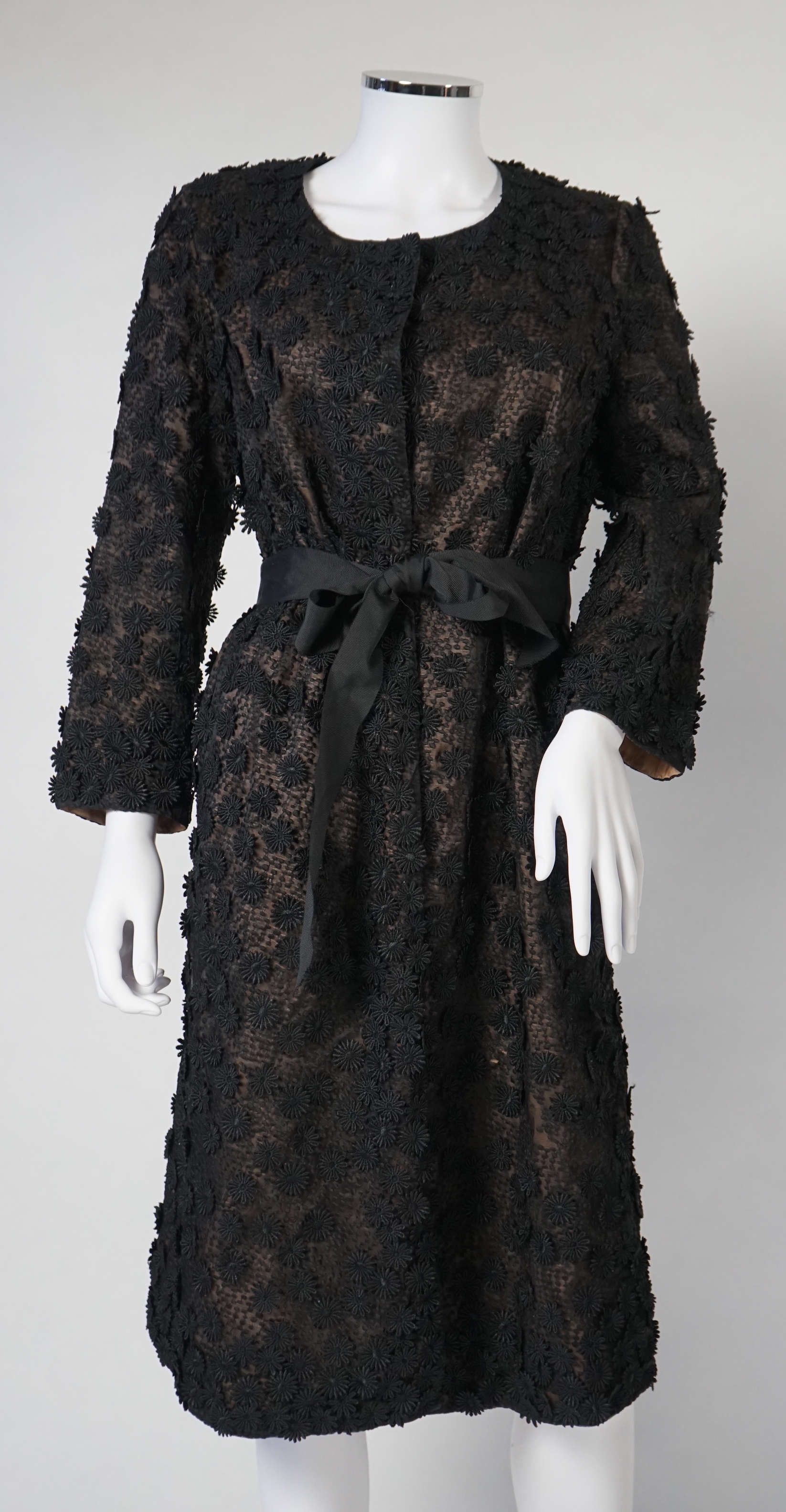 A Nicole Farhi lady's black lace knee length jacket with flower embellishment all over with black ribbon tie belt, size 12